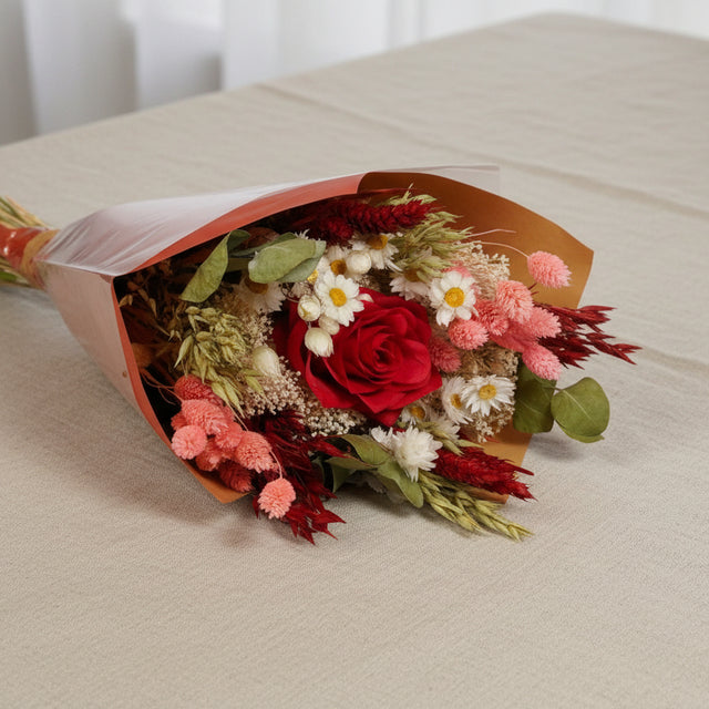 Bouquet fleurs séchées et artificielles rouge posé sur table