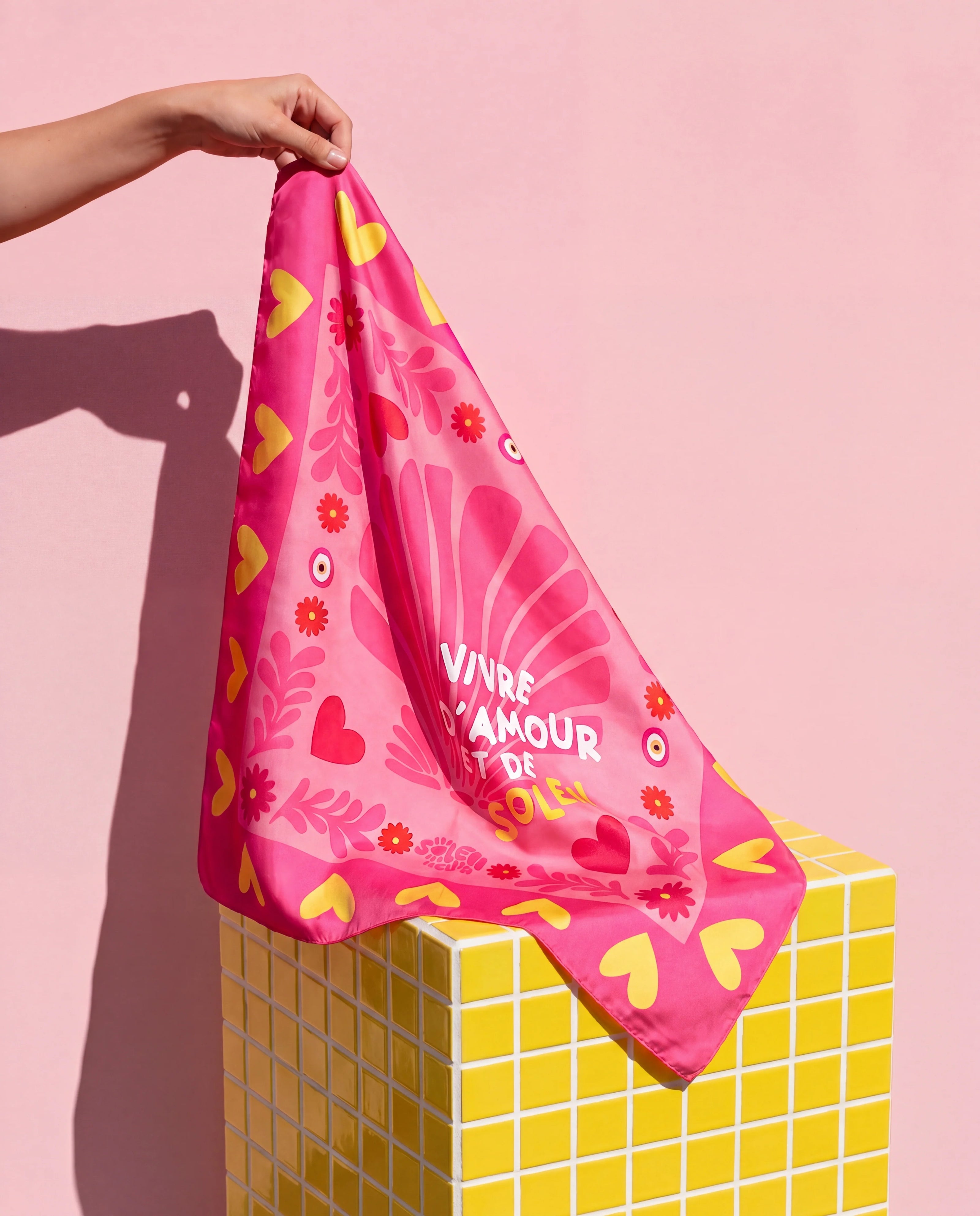 Foulard Amour & Soleil Soleil Mojito en satin rose, motif cœurs et fleurs, porté à la main