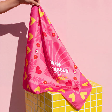 Foulard Amour & Soleil Soleil Mojito en satin rose, motif cœurs et fleurs, porté à la main