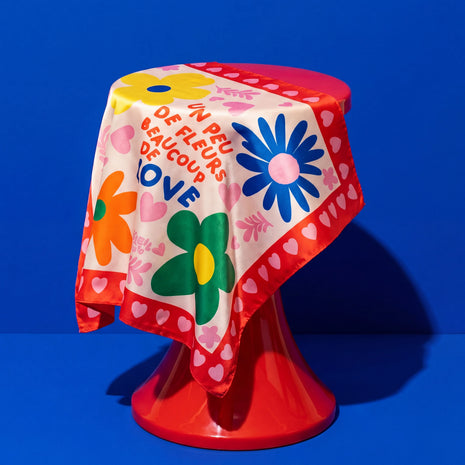 Foulard Fleurs & Love Soleil Mojito en satin coloré, motif fleurs et cœurs, drapé sur fond bleu